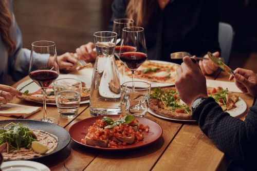 Gedeckter Tisch in der Pizzeria mit Pizzen, Vorspeisen und Rotwein