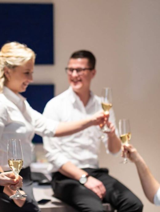 Hotel-Mitarbeiter beim gemeinsamen Anstoßen mit einem Glas Sekt