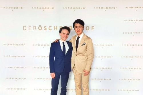 Music director Haiou Zhang poses with a colleague in front of the photo wall