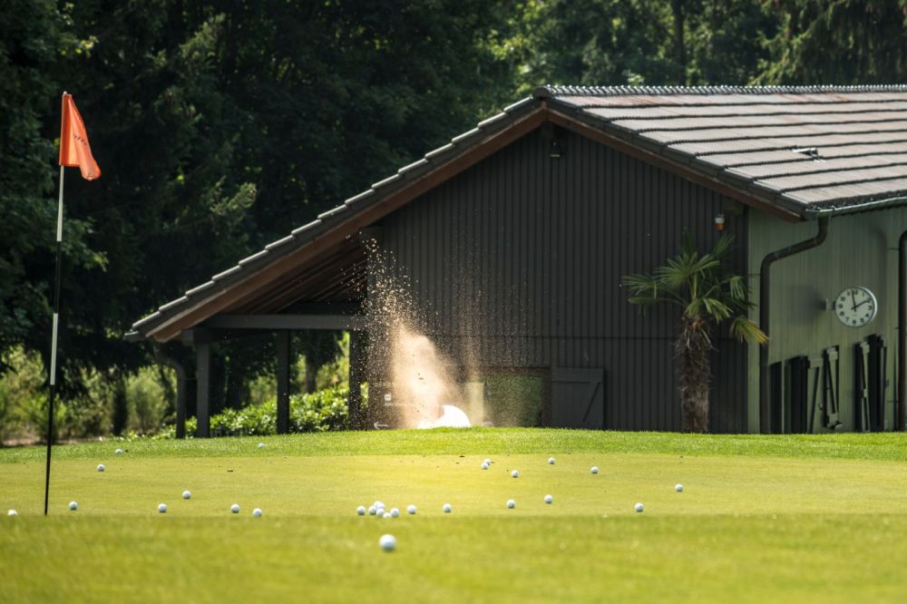 Golfübungsanglage mit vielen Golfbällen auf dem Platz bei Sonnenschein