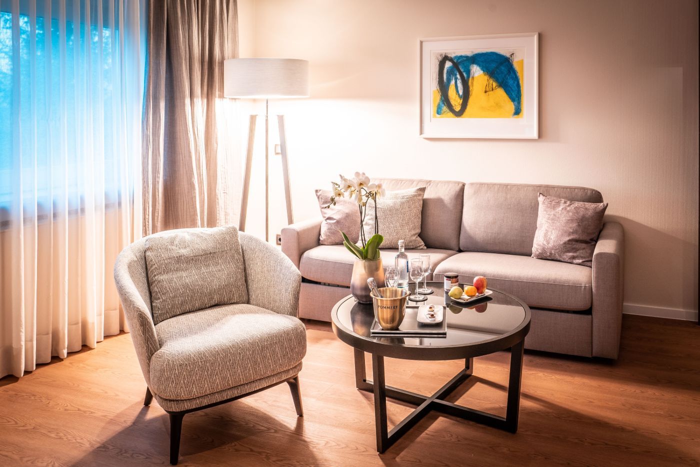 Wohnbereich mit Sessel, Couch und einem abstrakten Gemälde