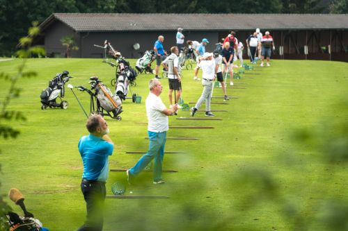 Eine Reihe an Golfern bei den Abschlägen im Golfhotel