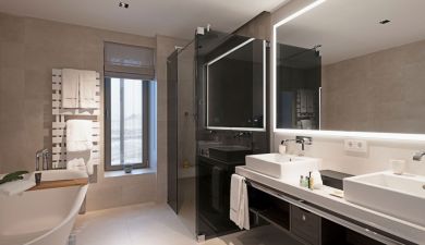 spacious bathroom with bathtub, shower, two sinks and a large lit mirror