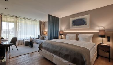 Blick auf ein Doppelbett neben dem Loungebereich mit Sofa und Beistelltisch im 5 Sterne Hotel im Schwarzwald