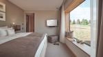 Lichtdurchflutetes Schlafzimmer mit großem Fenster, Fernseher und großem Fenster