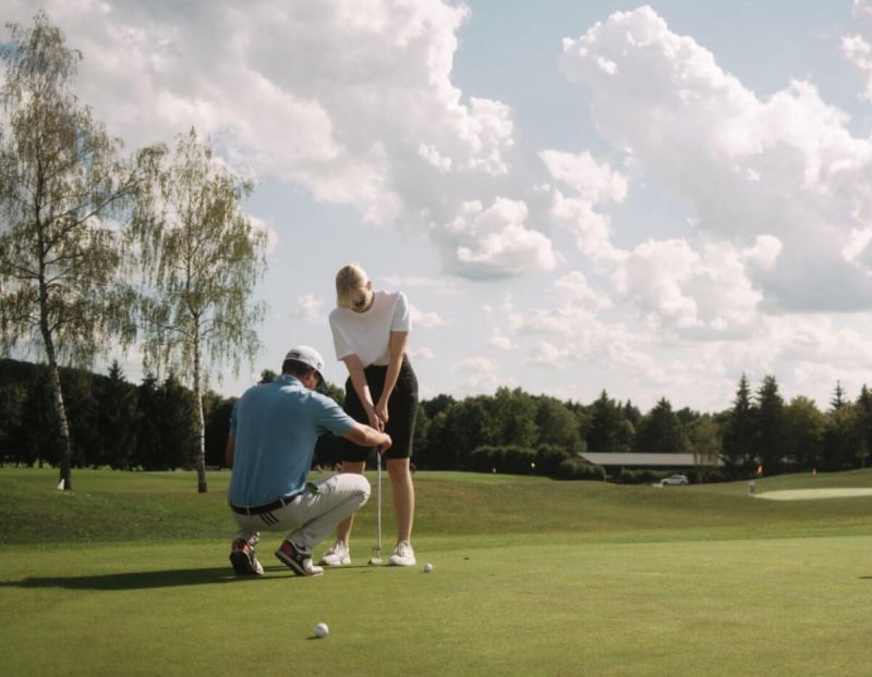 Eine Frau mit ihrem Golflehrer auf dem Golfplatz neben dem Tagungshotel im Schwarzwald