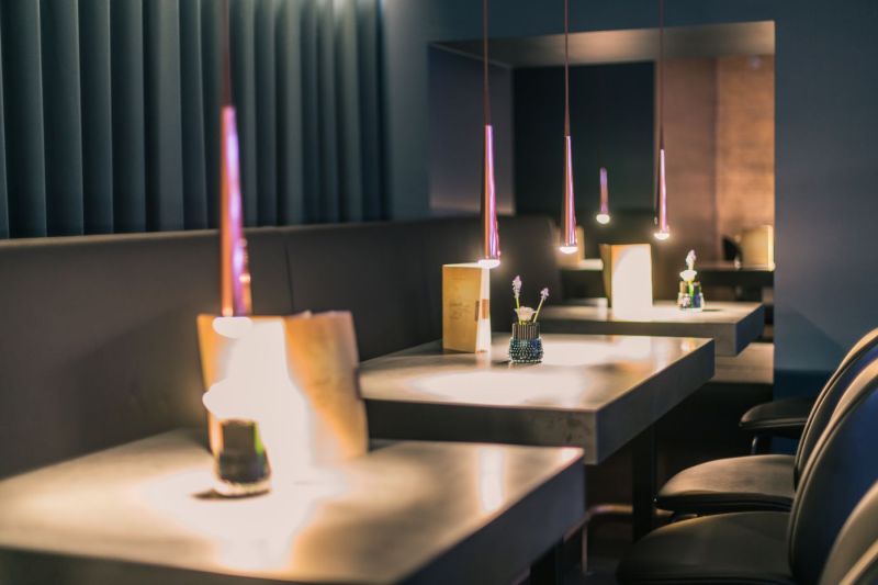 Mehrere atmosphärisch beleuchtete Tische in einer Bar