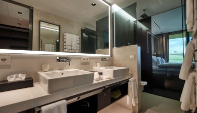 spacious bathroom with two sinks and a large lit mirror