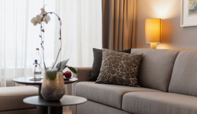 Gemütliche Couch an einem Beistelltisch mit frischem Obst und Wasser dekoriert mit einer weißen Orchidee