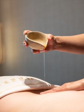 Masseur gießt Öl auf einen Rücken bei der Massage im 5 Sterne Hotel im Schwarzwald