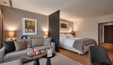 Offenes Premium Zimmer mit Wohn- und Schlafbereich ausgestattet mit einer Couch, Schreibtisch und gemütlichem Doppelbett