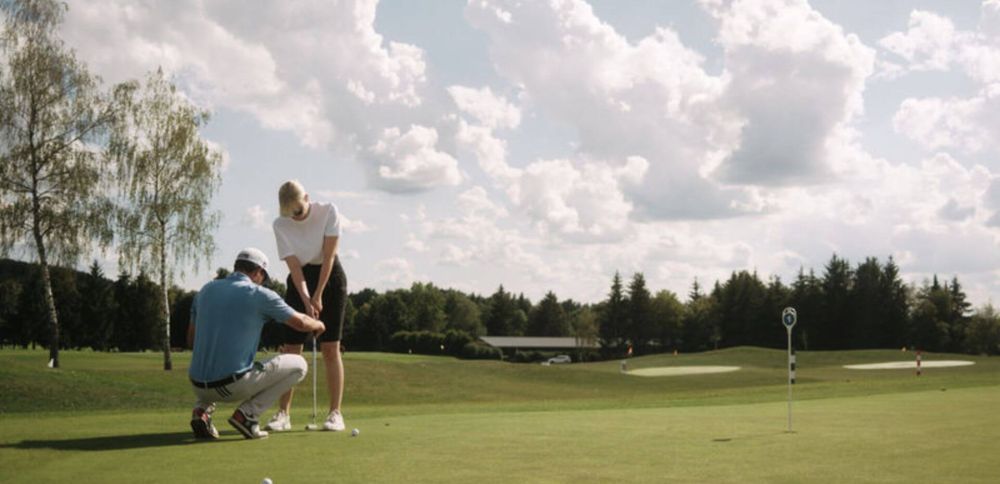 Golftrainer bringt einer Frau den Abschlag bei