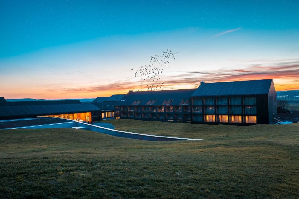 Blick auf die Außenfassade mit beleuchteten Zimmern des 5 Sterne Hotels im Schwarzwald in  der Abendröte