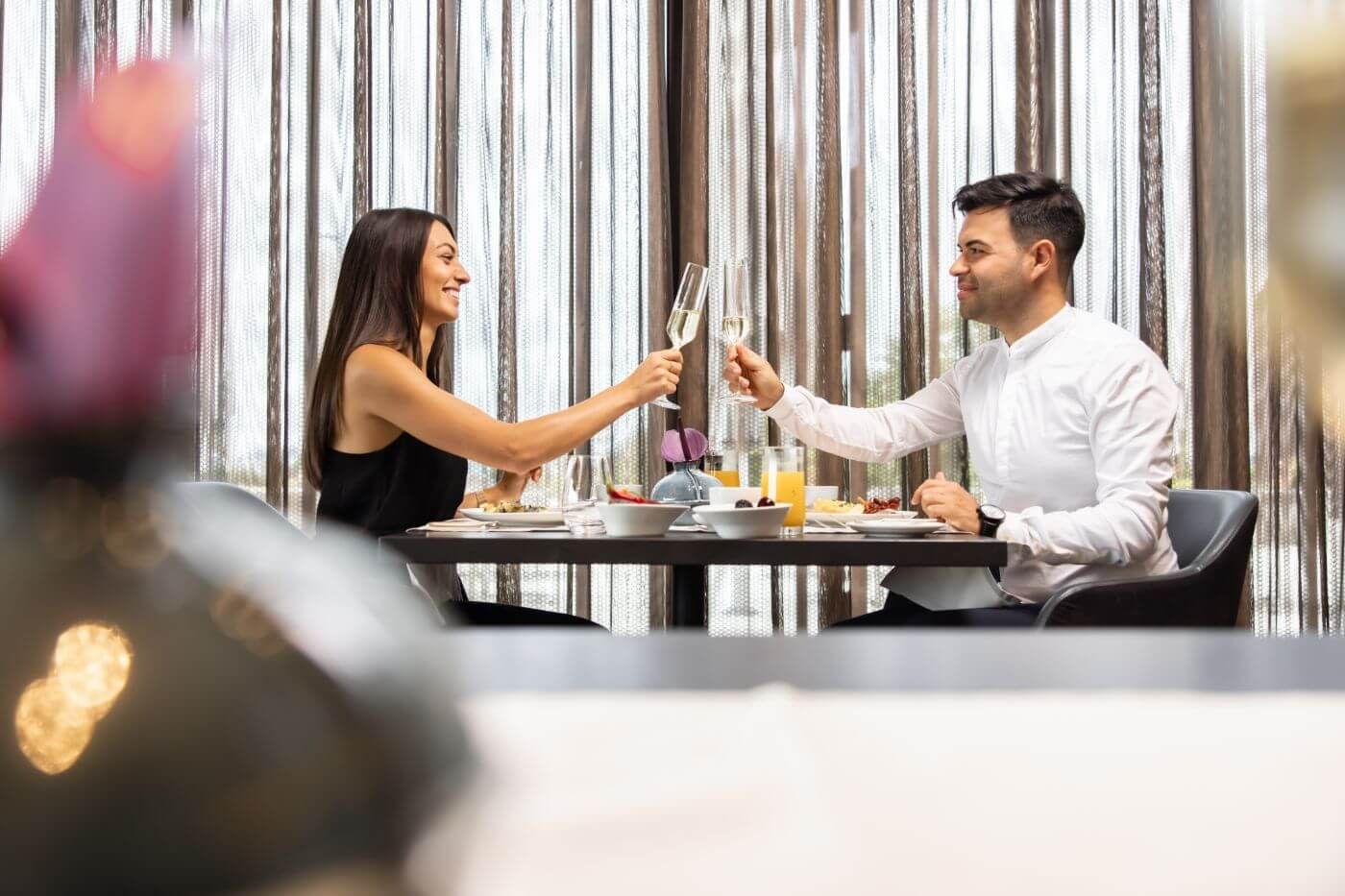 Paar sitzt in einem Restaurant und stößt mit Champagner an