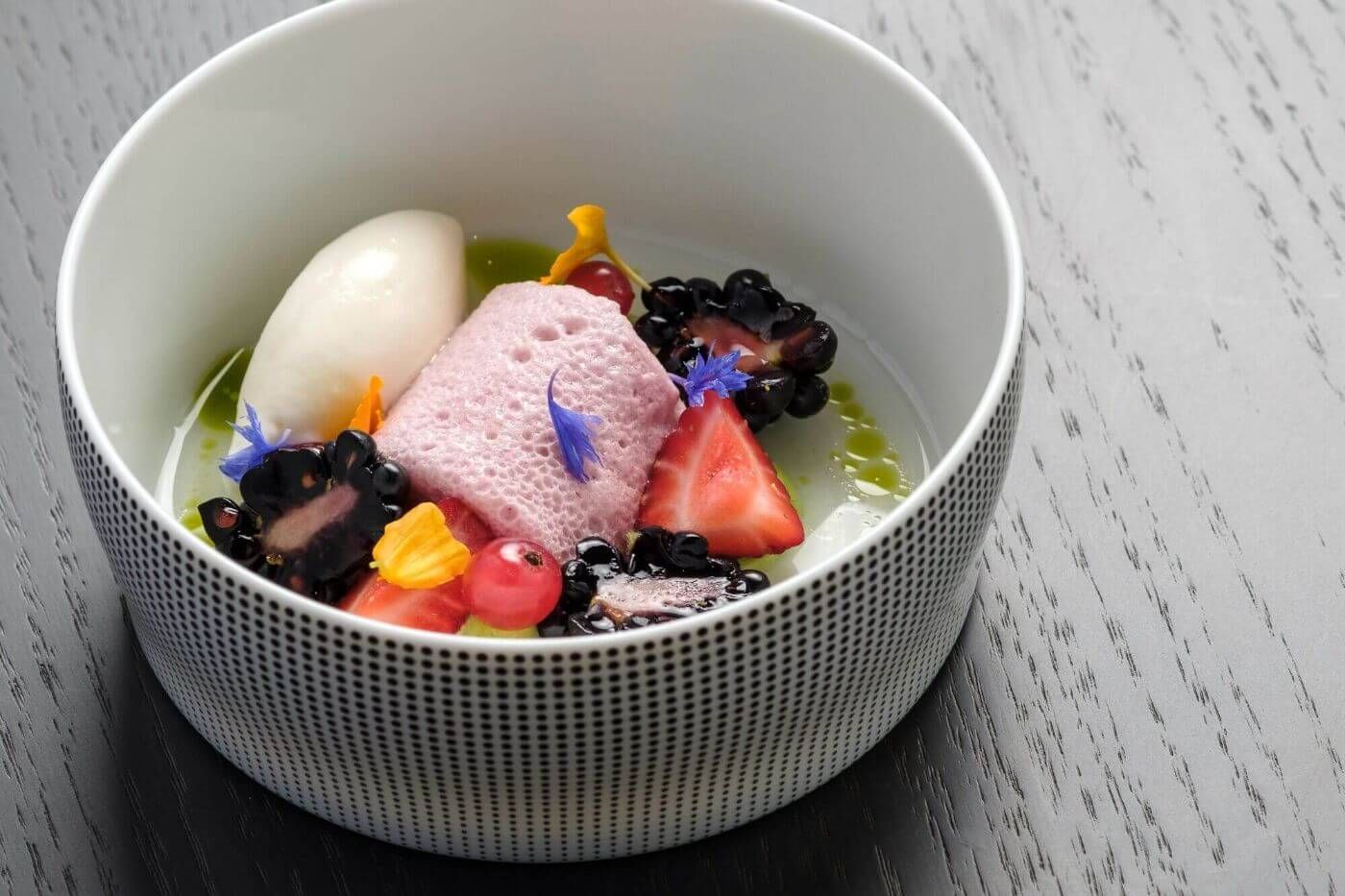 Ansprechend angerichtetes Dessert mit frischen Beeren, Blüten und Mousse