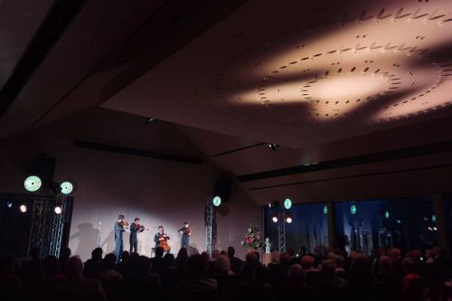 Two string players perform a concert on an illuminated stage
