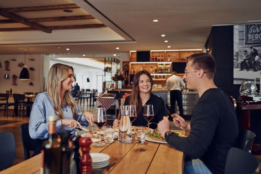 Drei Personen essen gemeinsam Pizza im italienischen Restaurant Hexenweiher